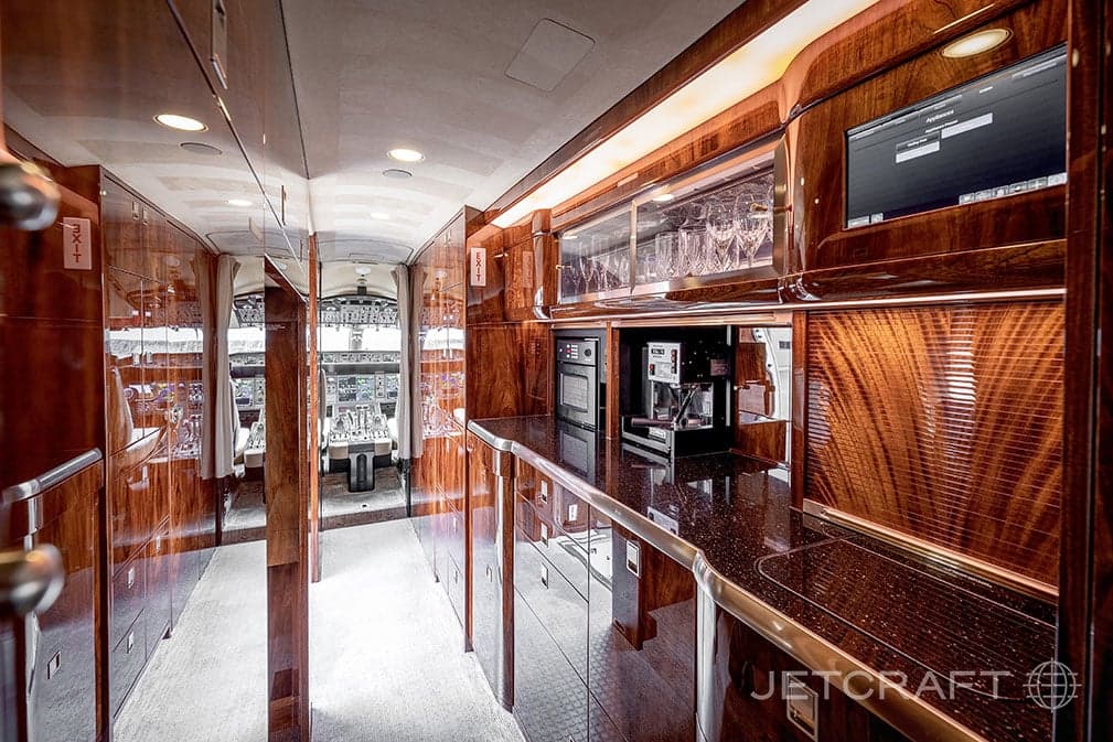 View of the aircraft cabin with a galley and cockpit in the background.