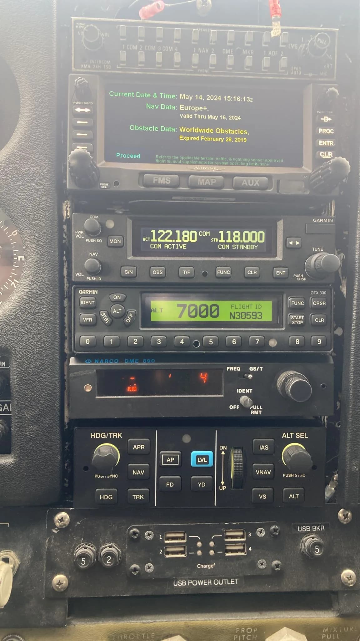 A close-up view of the avionics stack in an aircraft cockpit, showing radios, transponder with N30593, and USB power outlets.