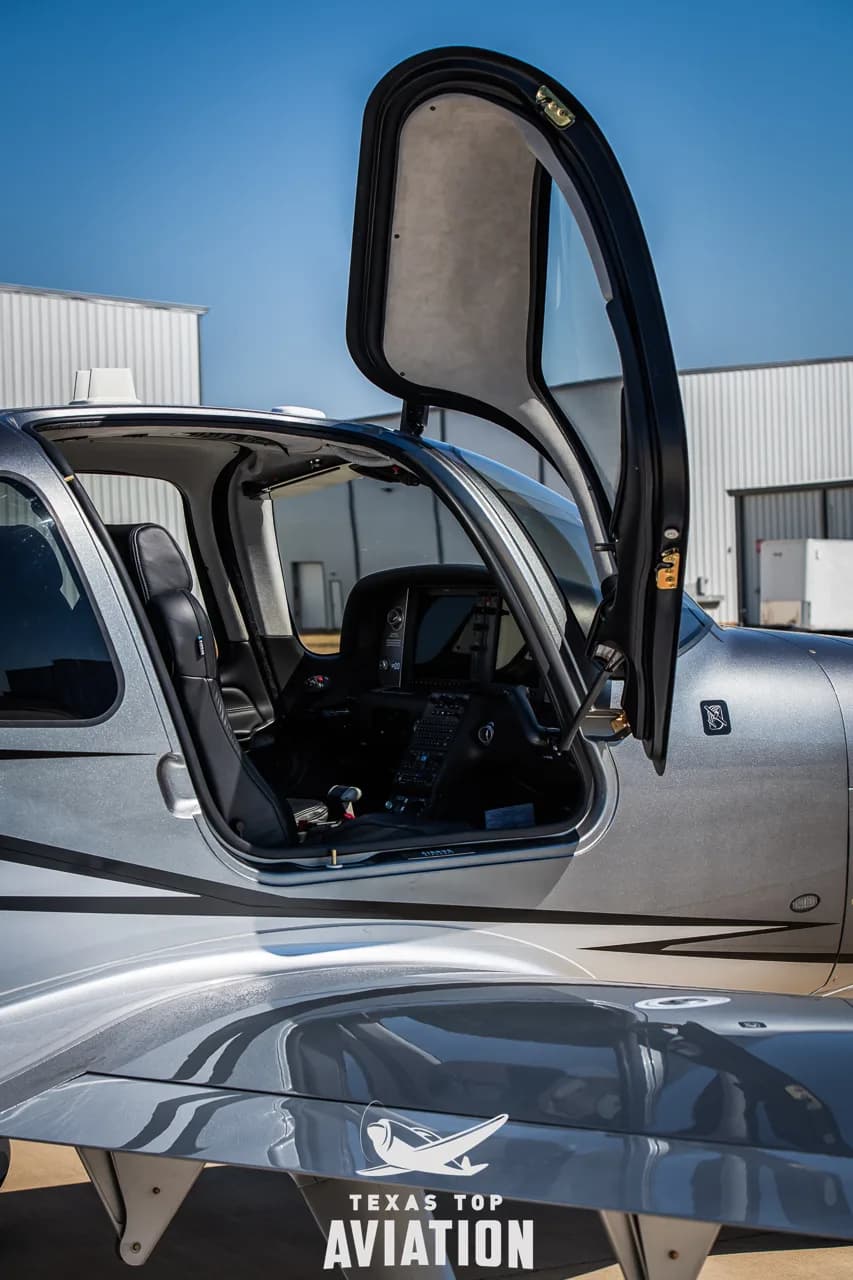 A view into the cockpit and cabin of the Cirrus SR22 aircraft through an open door.