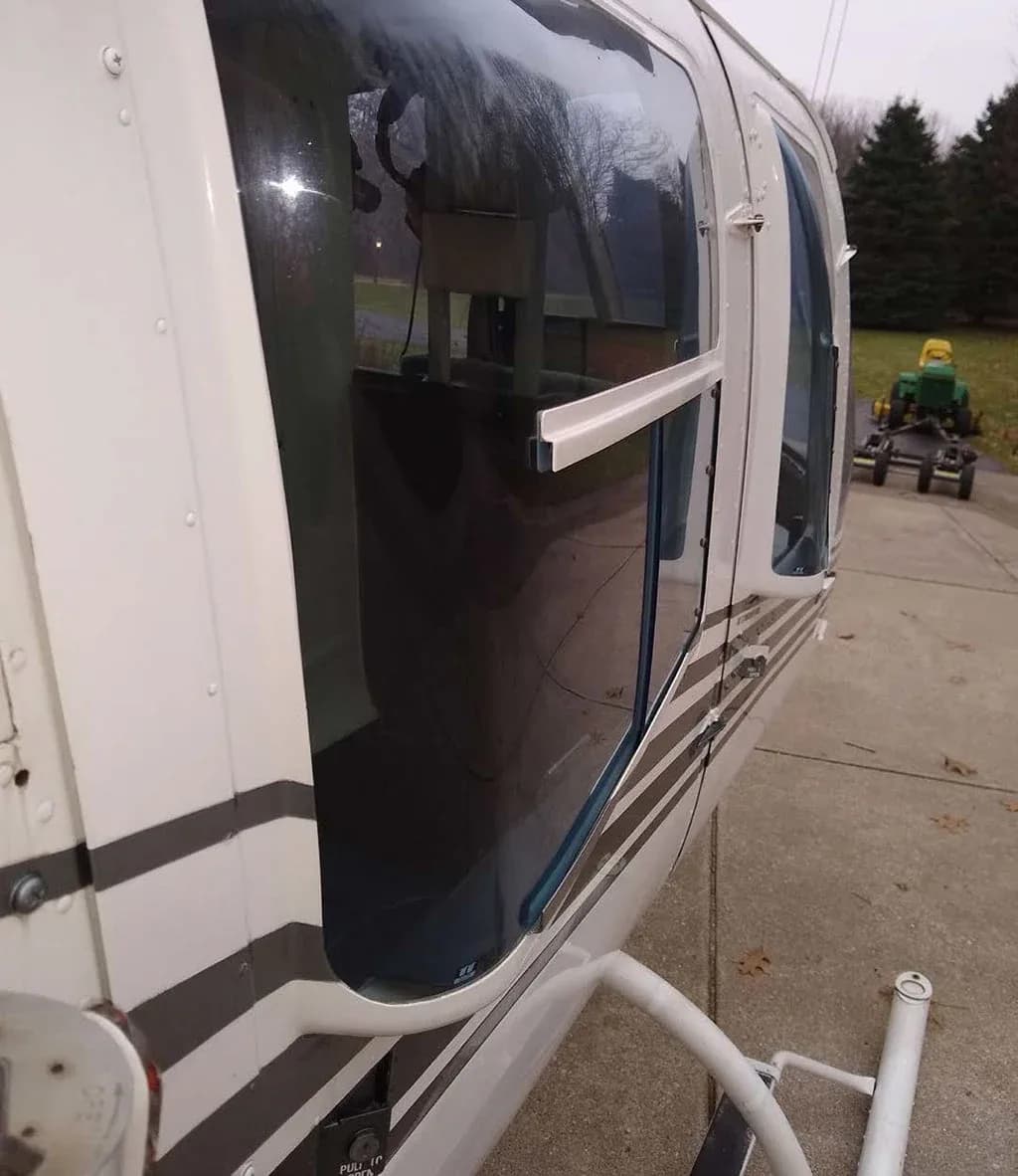 Close-up of the side of a white helicopter, showing the passenger windows and part of the landing skids.