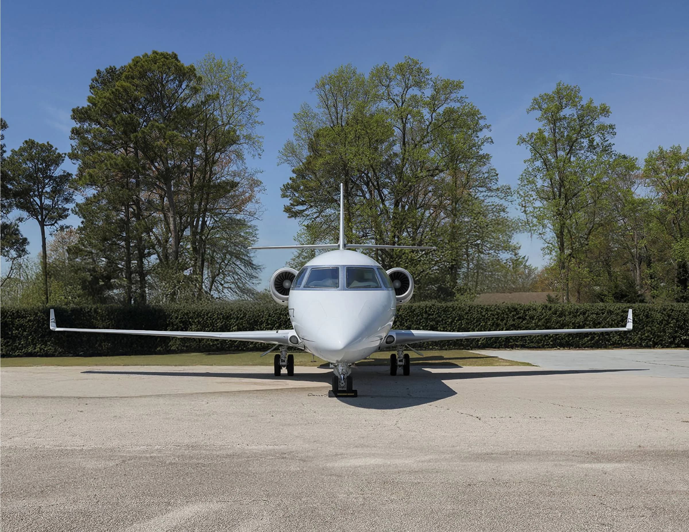 Front view of a white aircraft with blue accents parked on the tarmac.