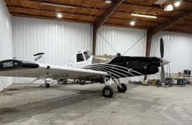 A black and white Air Tractor crop duster sits in a hangar.