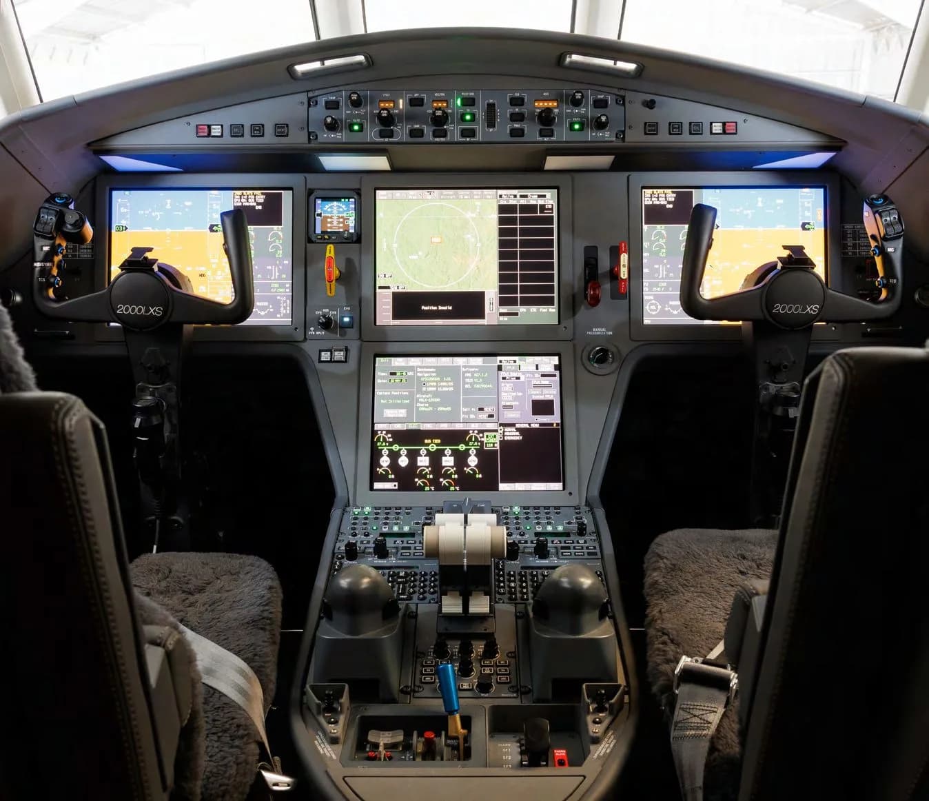 The modern cockpit of a Dassault Falcon 2000LXS with multiple large digital displays and control yokes.