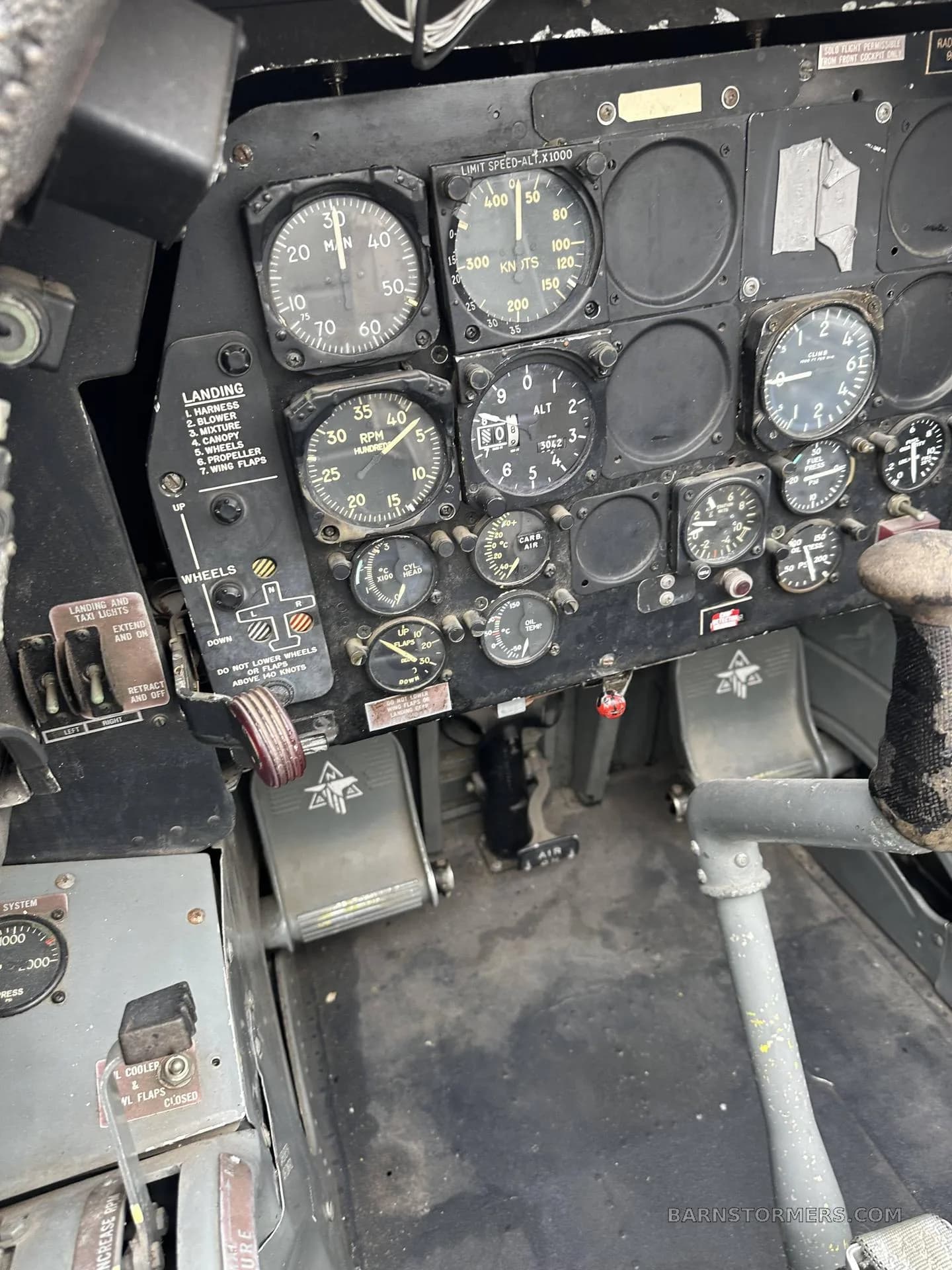 A view of the instrument panel, rudder pedals, and floor of a vintage aircraft cockpit.