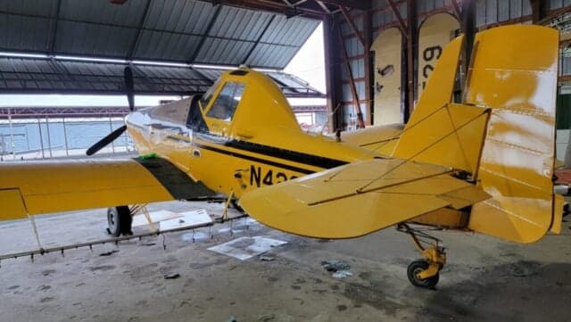 A yellow and black Air Tractor AT-400 sits inside a hangar.