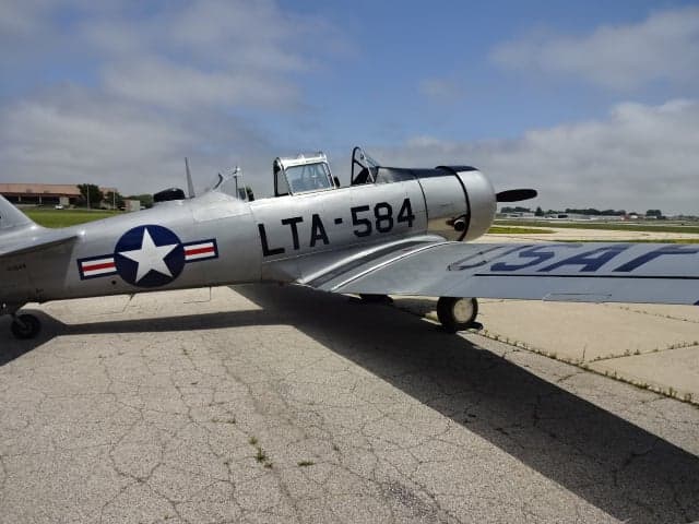 Side view of the silver T-6 Texan aircraft on the tarmac.