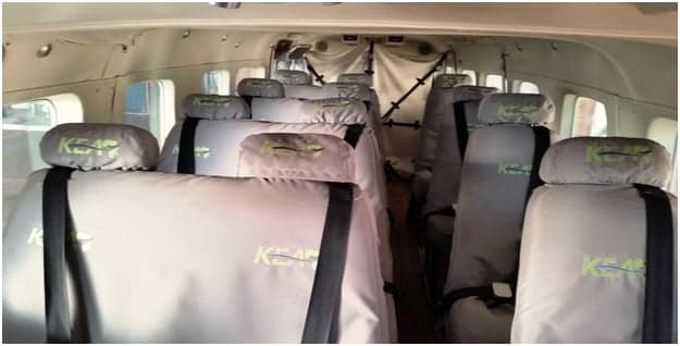 The aircraft's passenger cabin features multiple rows of grey fabric seats, each with a "KEAP" logo on the headrest.