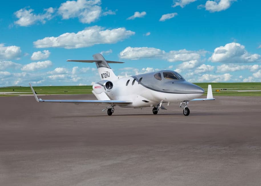 A white and grey HondaJet, registration N72HJ, is parked on a concrete tarmac, viewed from the front-right.