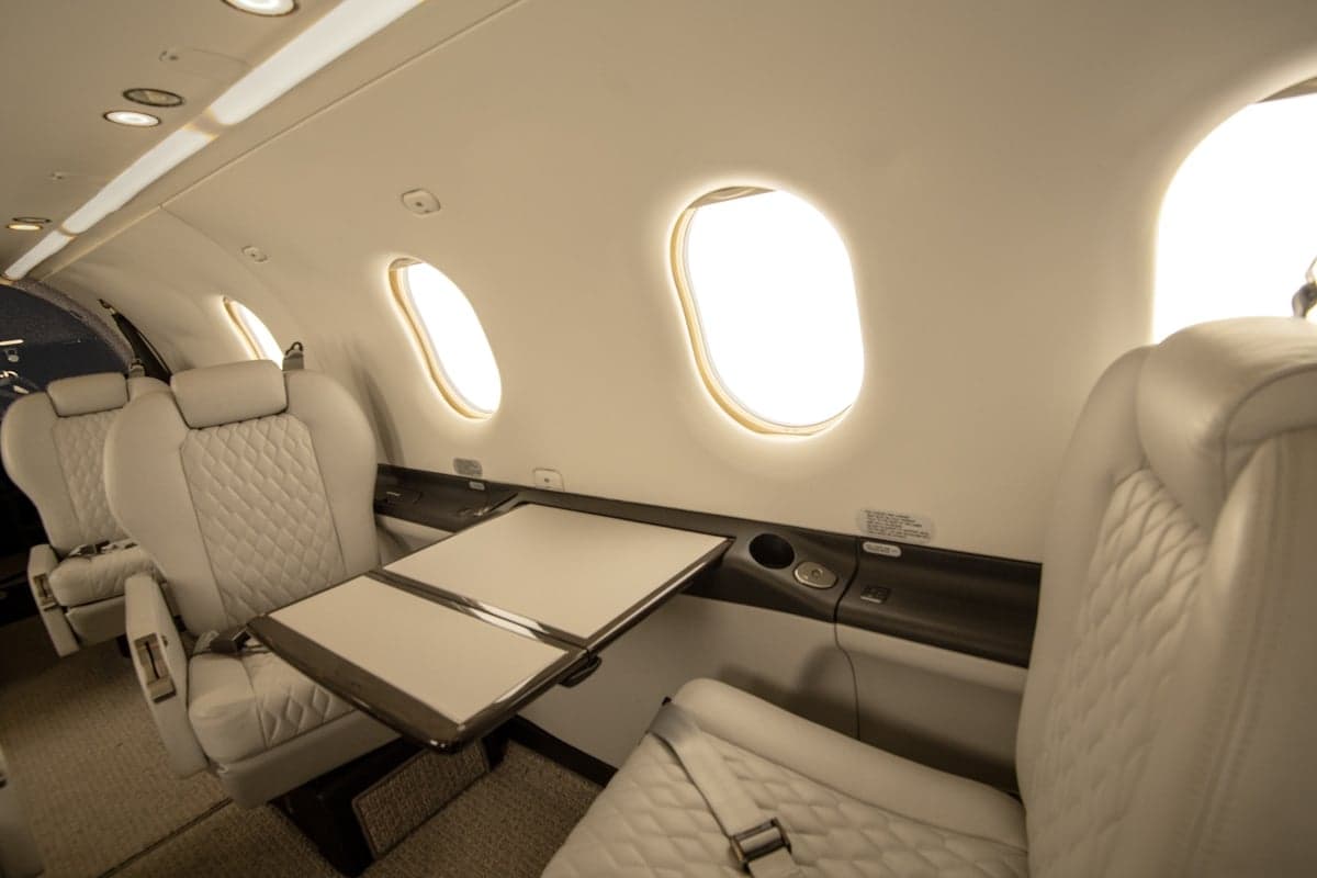 Close-up of the aircraft cabin featuring white leather seats and a folding table.