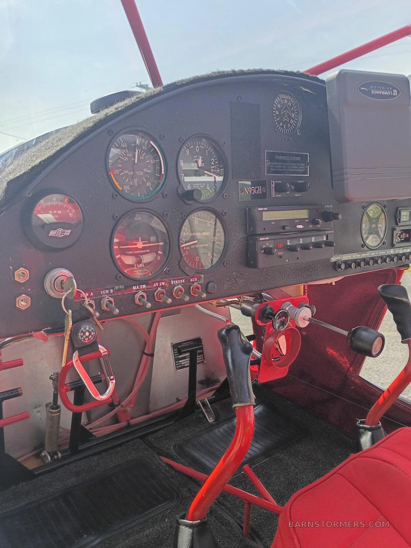 The cockpit of a SkyStar Kitfox aircraft features a black instrument panel with analog gauges and red controls.