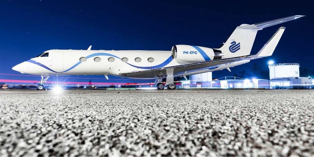 A side view of the P4-EFC aircraft with a white and blue paint scheme on the tarmac at night.