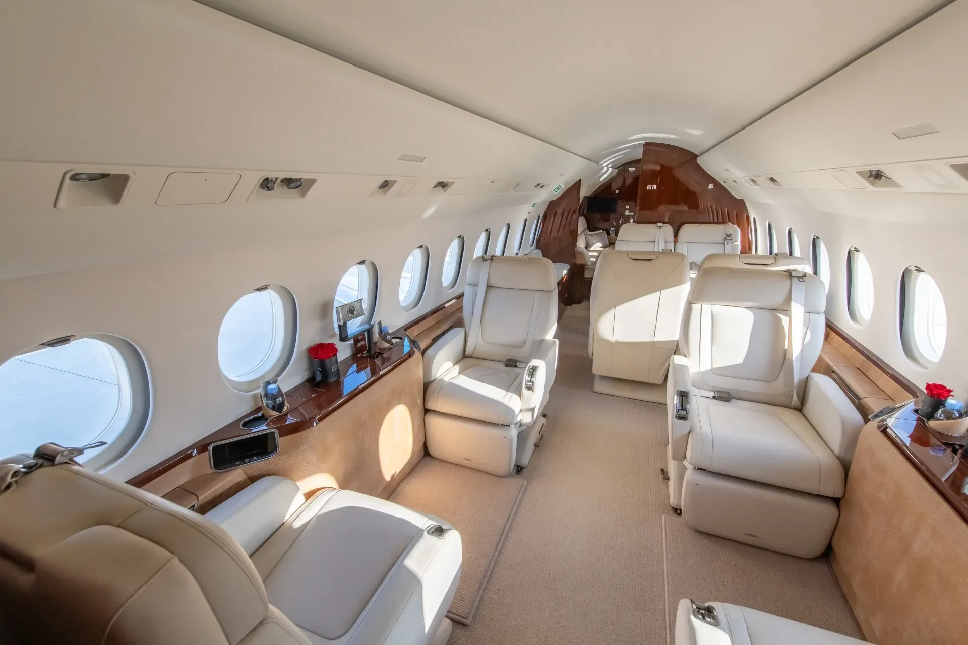 The luxurious interior cabin of a business jet, featuring cream leather seats and polished wood accents.