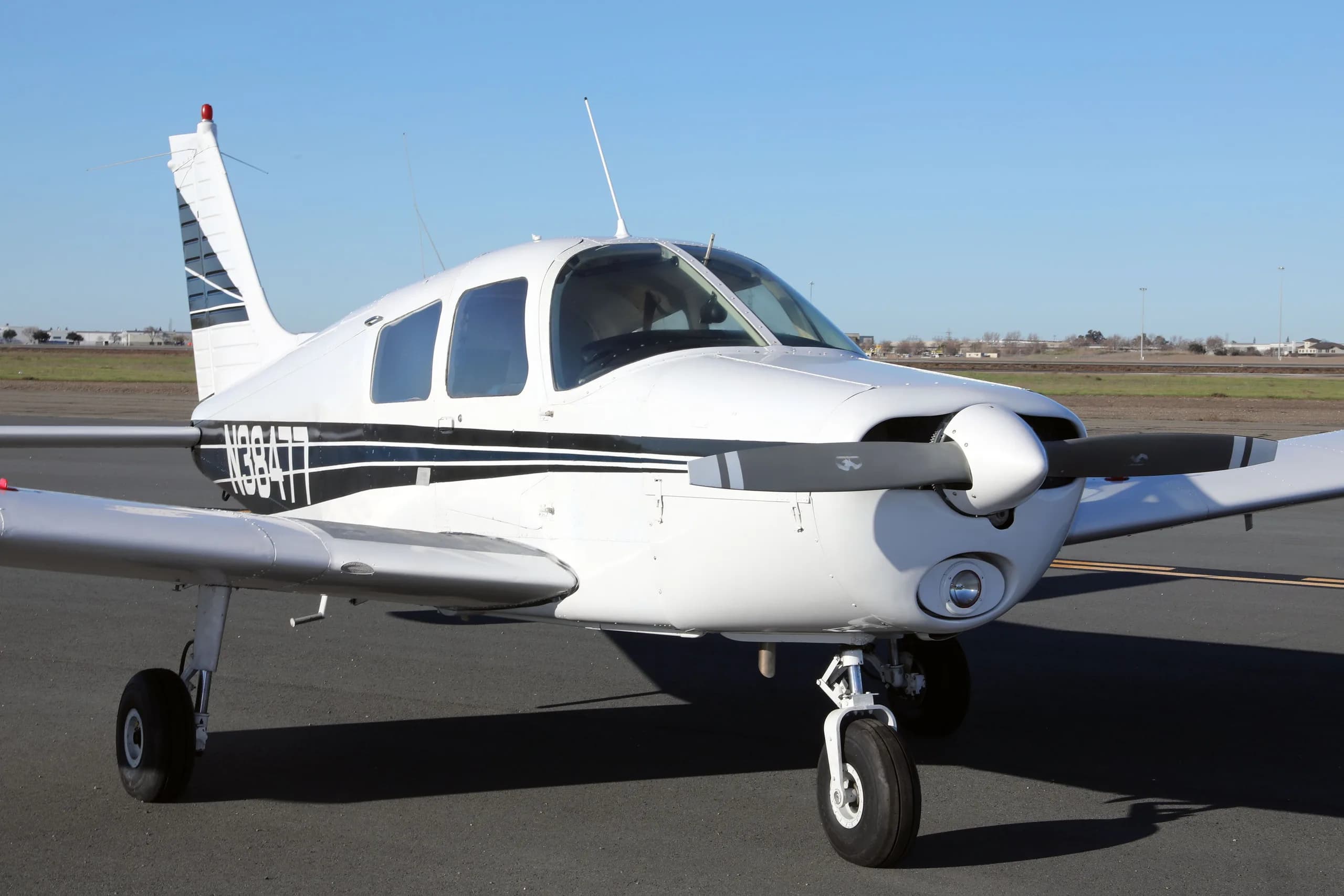 A close-up front three-quarter view of the white Piper Cherokee N38477 with its propeller.