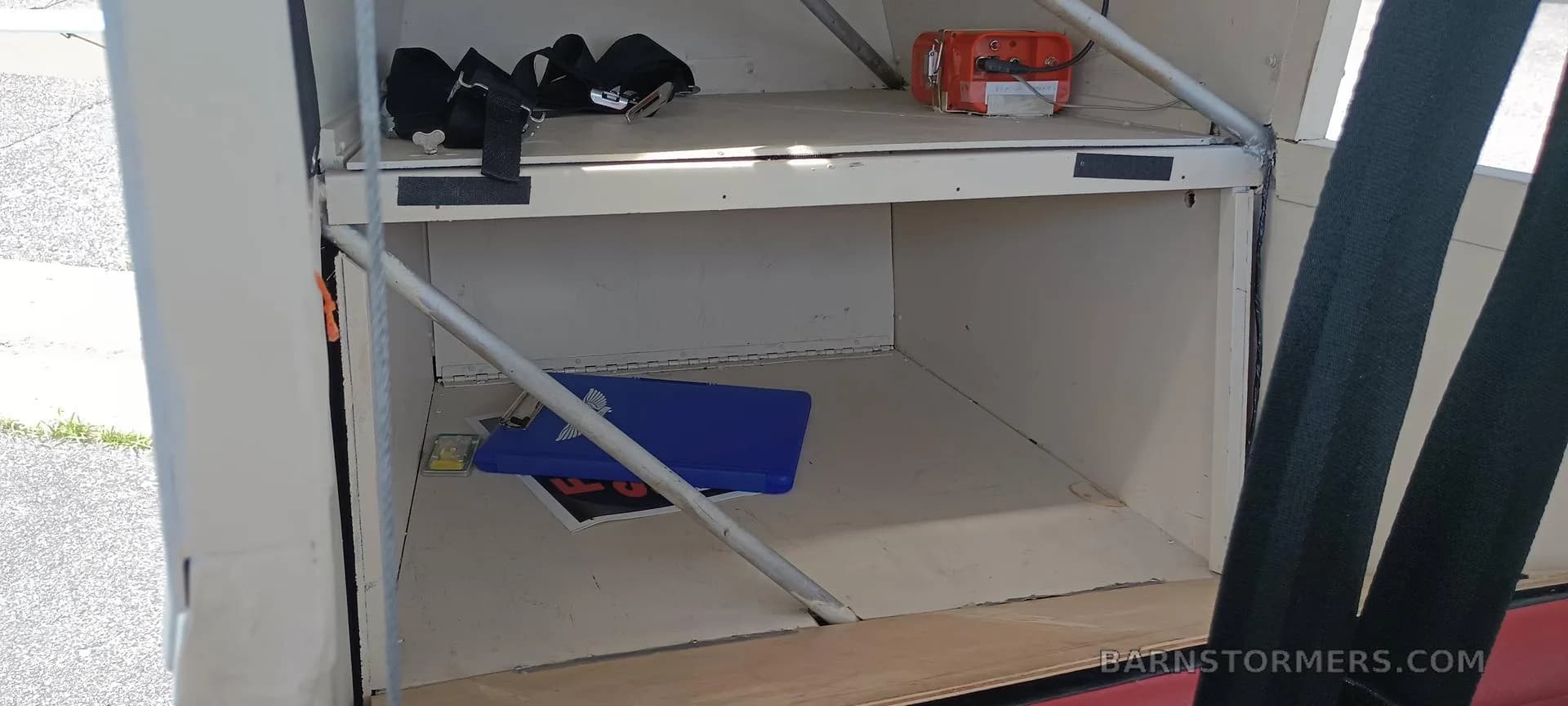 The rear cargo or storage area of a small aircraft, showing an open compartment with a blue case.