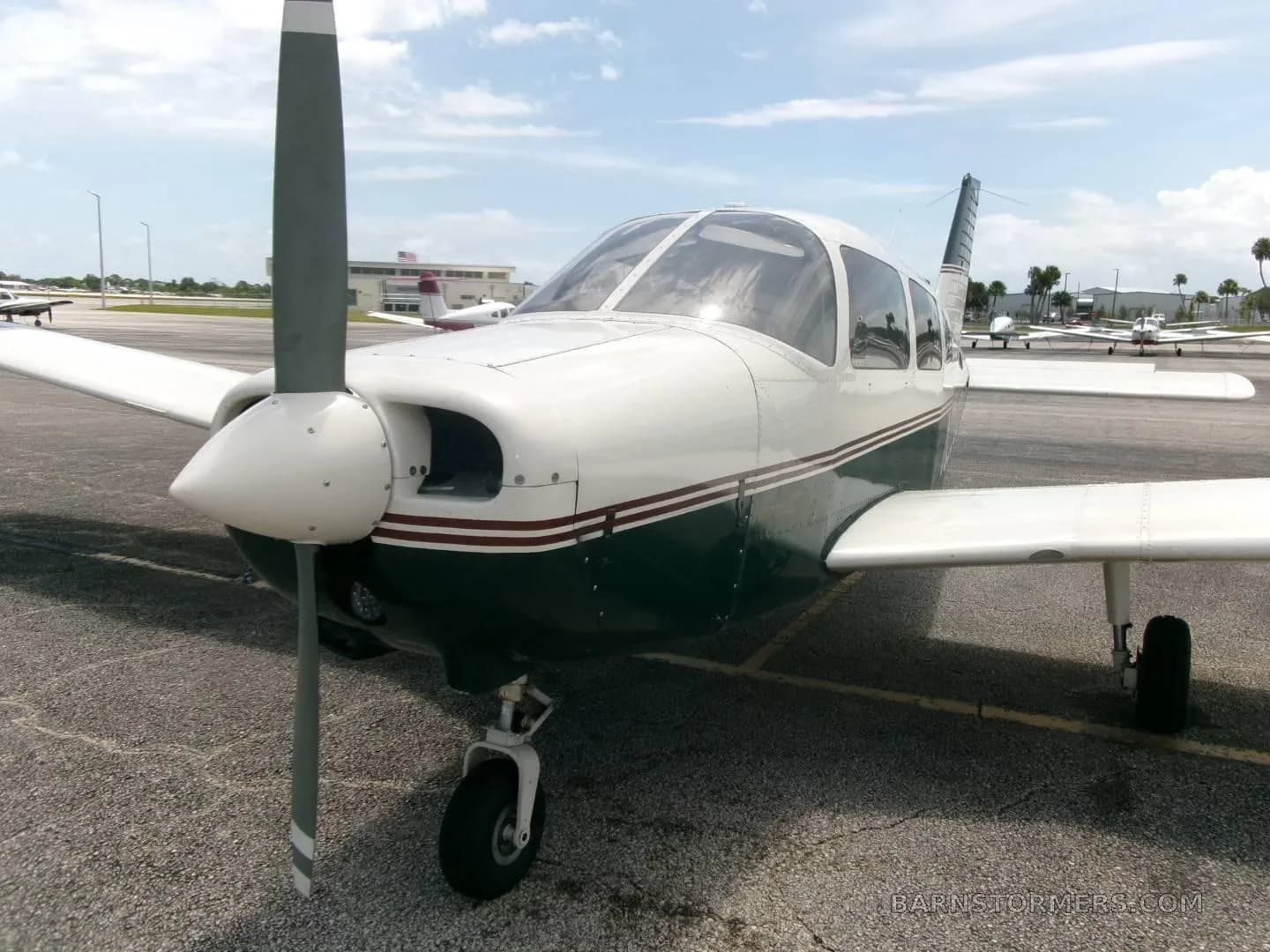 A front view of a white and dark green Piper Archer II (N334AC) with its propeller, parked on an airfield.