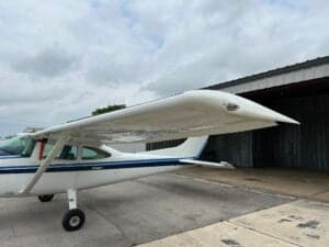 Close-up of the wing and fuselage of a Cessna aircraft with a white and blue paint scheme.