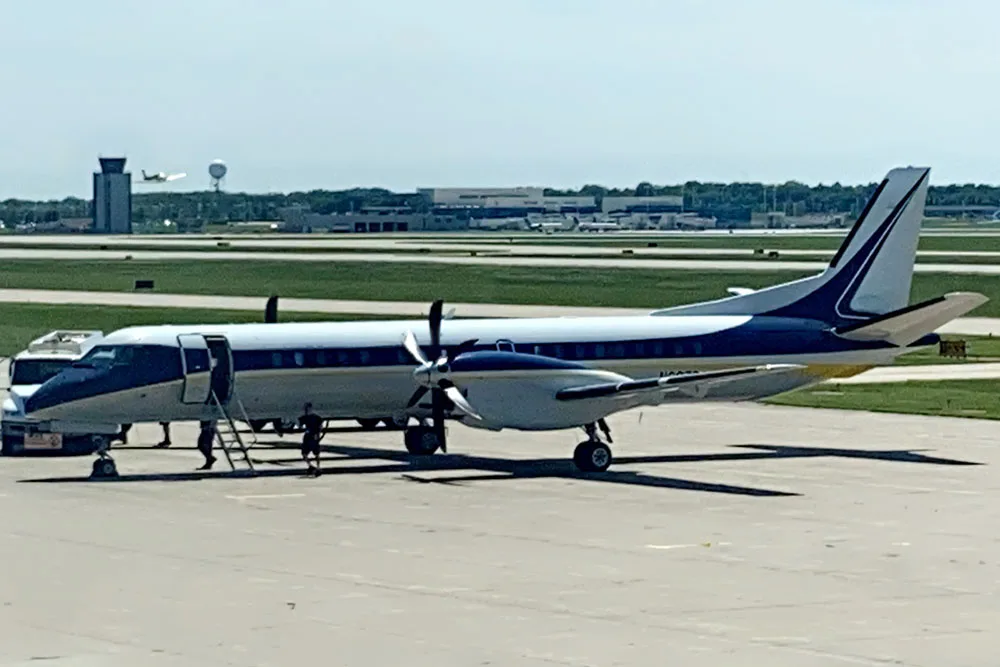 Side view of a blue and white aircraft parked at an airport.