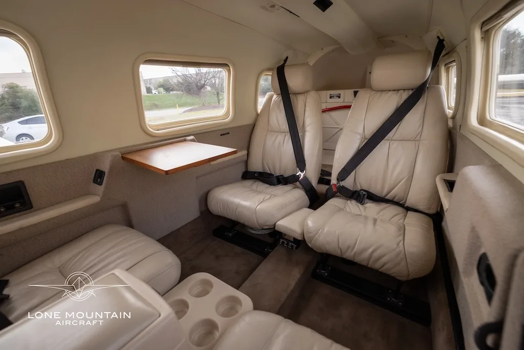 A view of the beige leather interior cabin, showing two rear-facing seats with a table and a side view of the forward-facing seats.