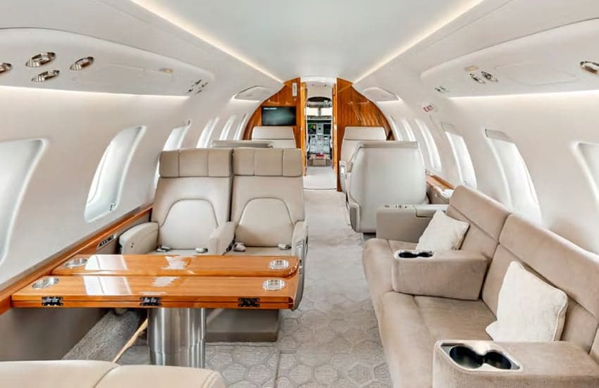 The aircraft's interior features leather seats and a wooden table.