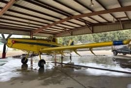 A yellow Air Tractor aircraft parked inside a hangar, side view.