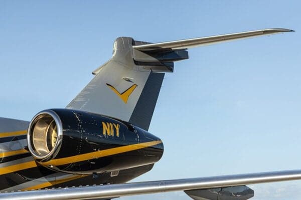A close-up of the tail and engine of the N1Y Embraer Legacy 500, showing the black and yellow paint scheme.