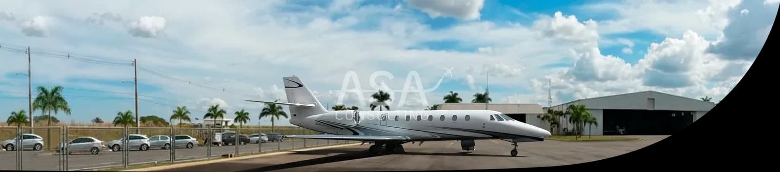 A white Cessna Citation CJ3 parked on the tarmac in front of a hangar.