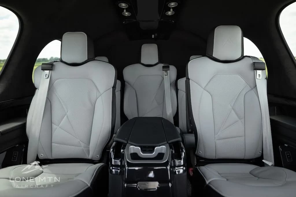 The rear cabin interior of a Cirrus Vision Jet, showing three light gray leather seats with geometric stitching.