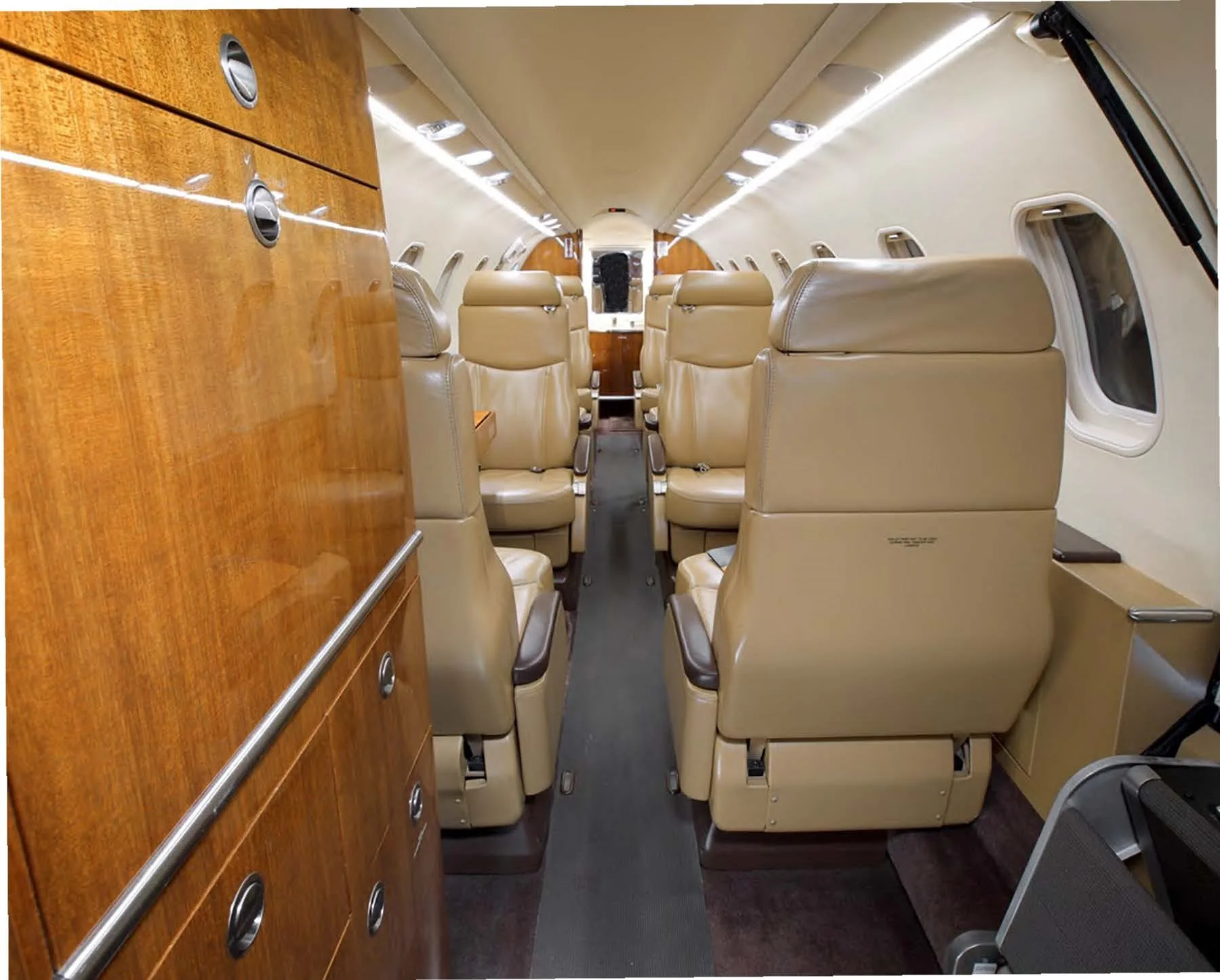 Aircraft cabin interior with leather seats and wood paneling.