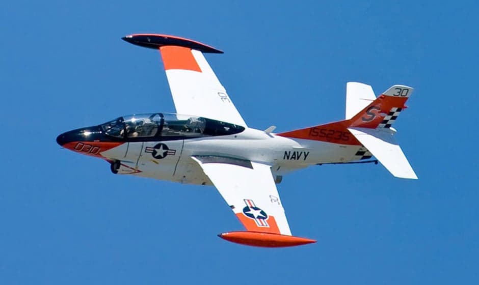 A T-2B Buckeye aircraft in flight against a blue sky.