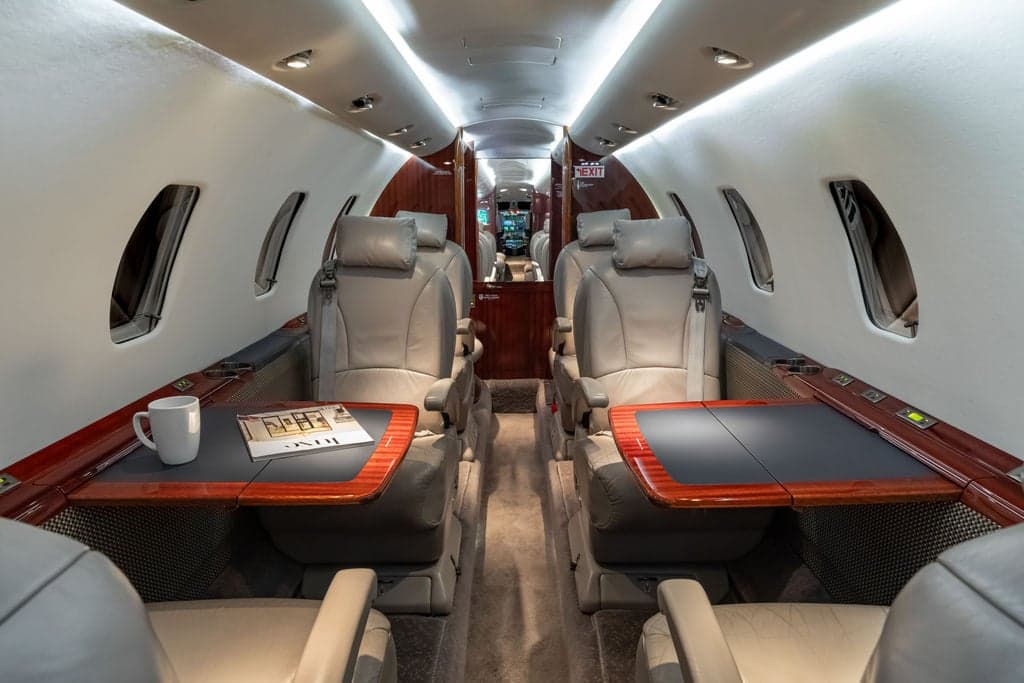 Interior of a Cessna Citation CJ3+ aircraft, showing the seating arrangement and tables.