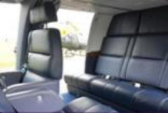 Interior view of the helicopter cabin with black leather seats.