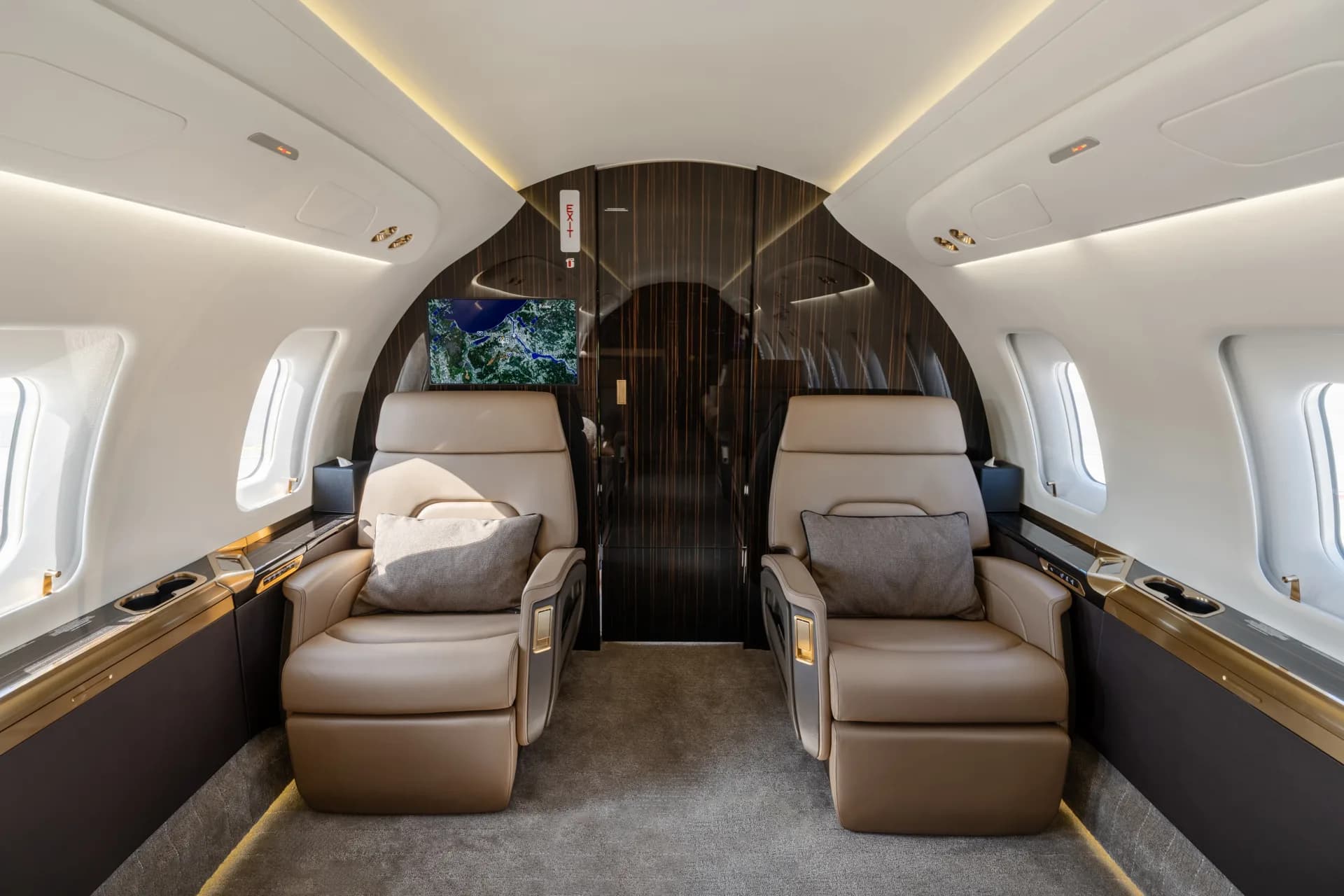 A view of the forward section of the aircraft cabin with two plush brown leather seats facing each other.