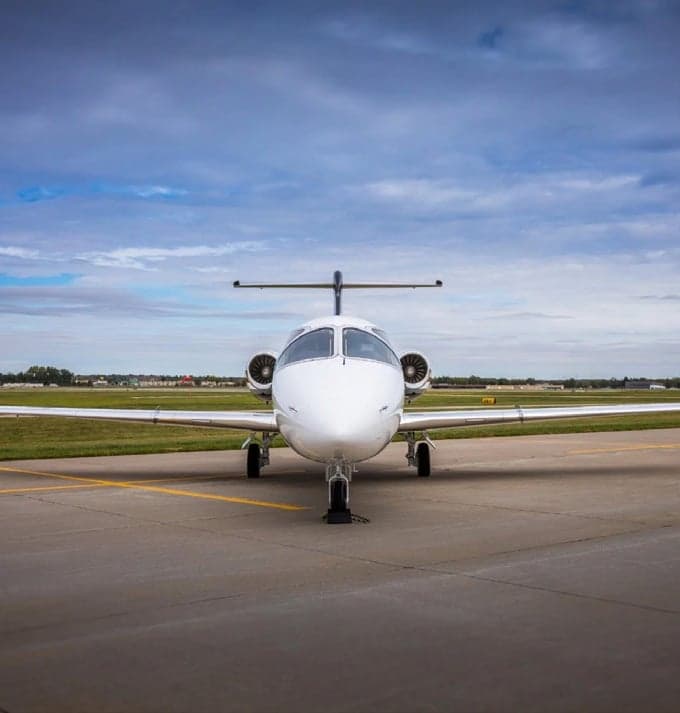 Front view of a white jet aircraft on the tarmac.