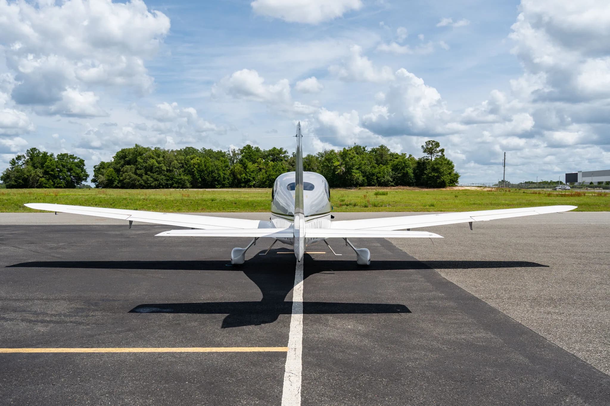 Rear view of a silver Cirrus SR22 aircraft parked on an airfield.