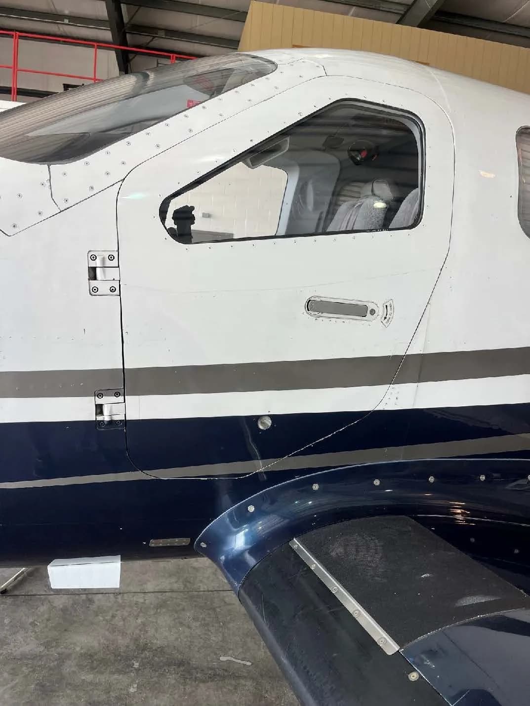 A close-up view of the cockpit door and fuselage of a white and blue aircraft.