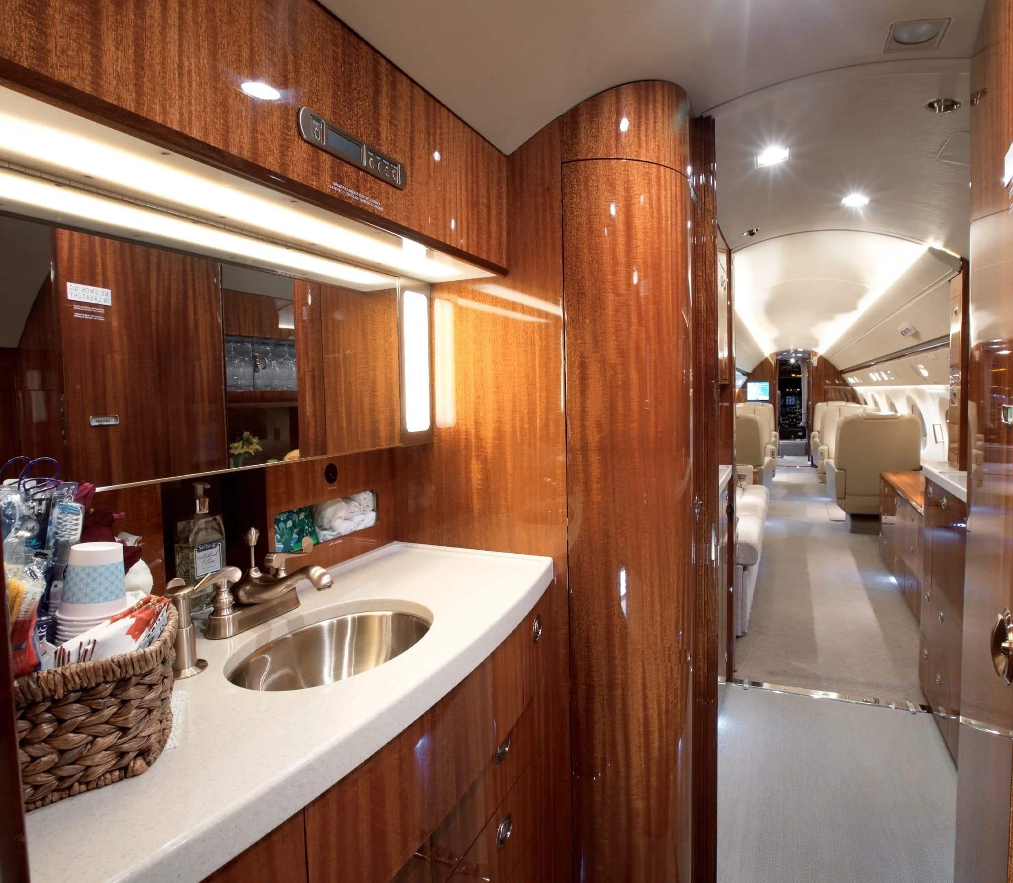 The private jet's lavatory features a modern sink, mirror, and elegant wood paneling, with the cabin visible in the background.