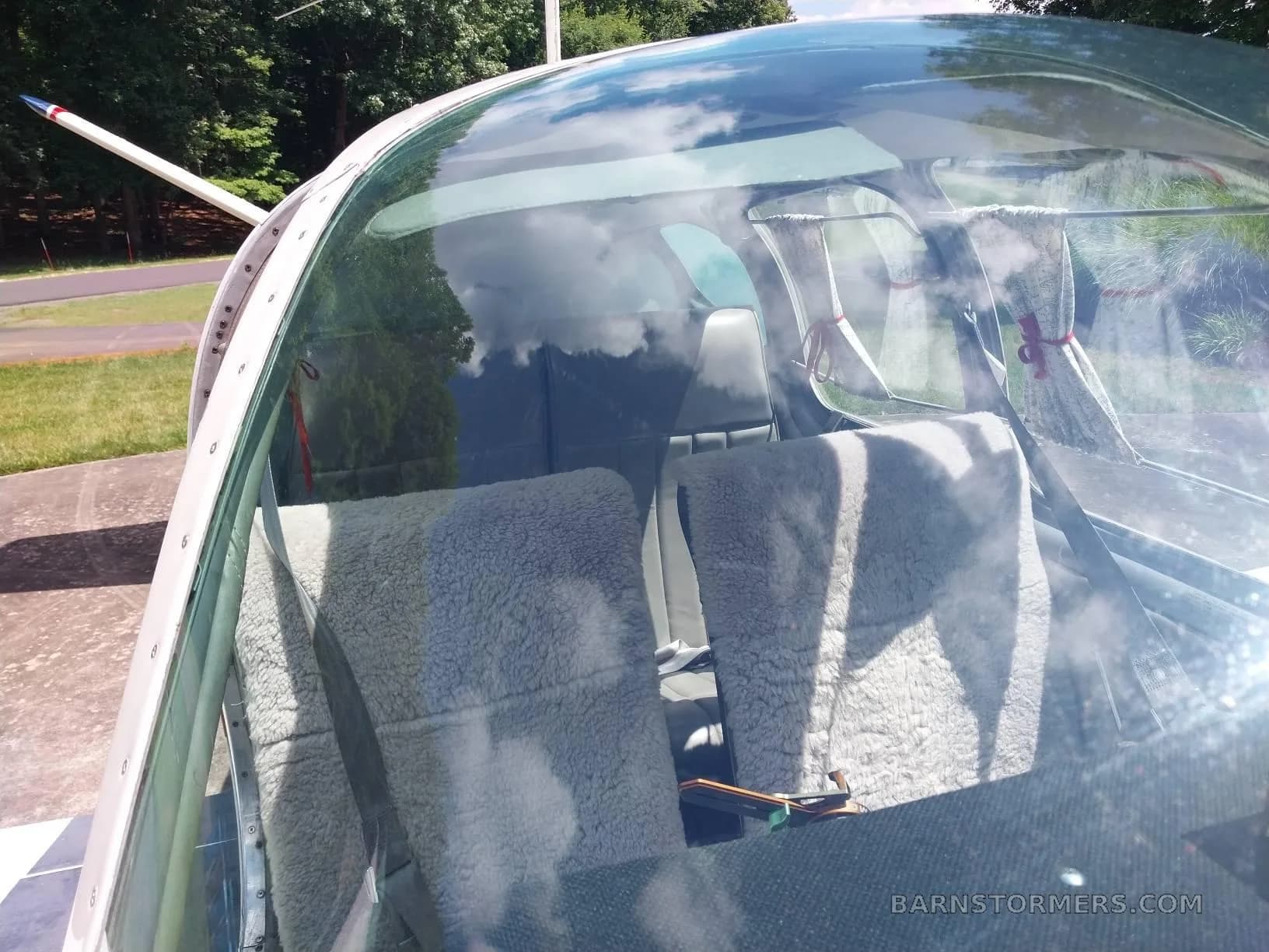 The interior of a Beechcraft Bonanza, showing two front seats covered with sheepskin, viewed through the canopy.