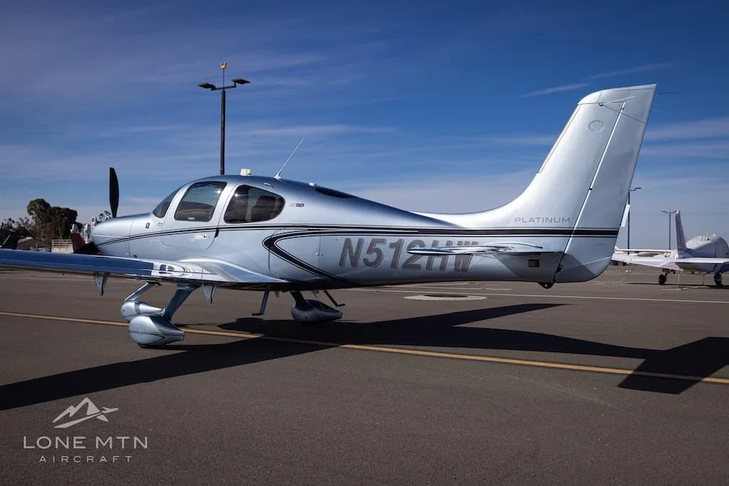 Rear-left side view of a silver Cirrus SR22 aircraft, N512HW, parked on an airfield.