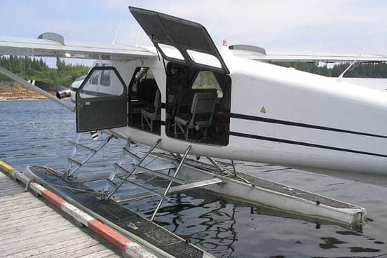A de Havilland Beaver floatplane is docked at a pier with the doors open.