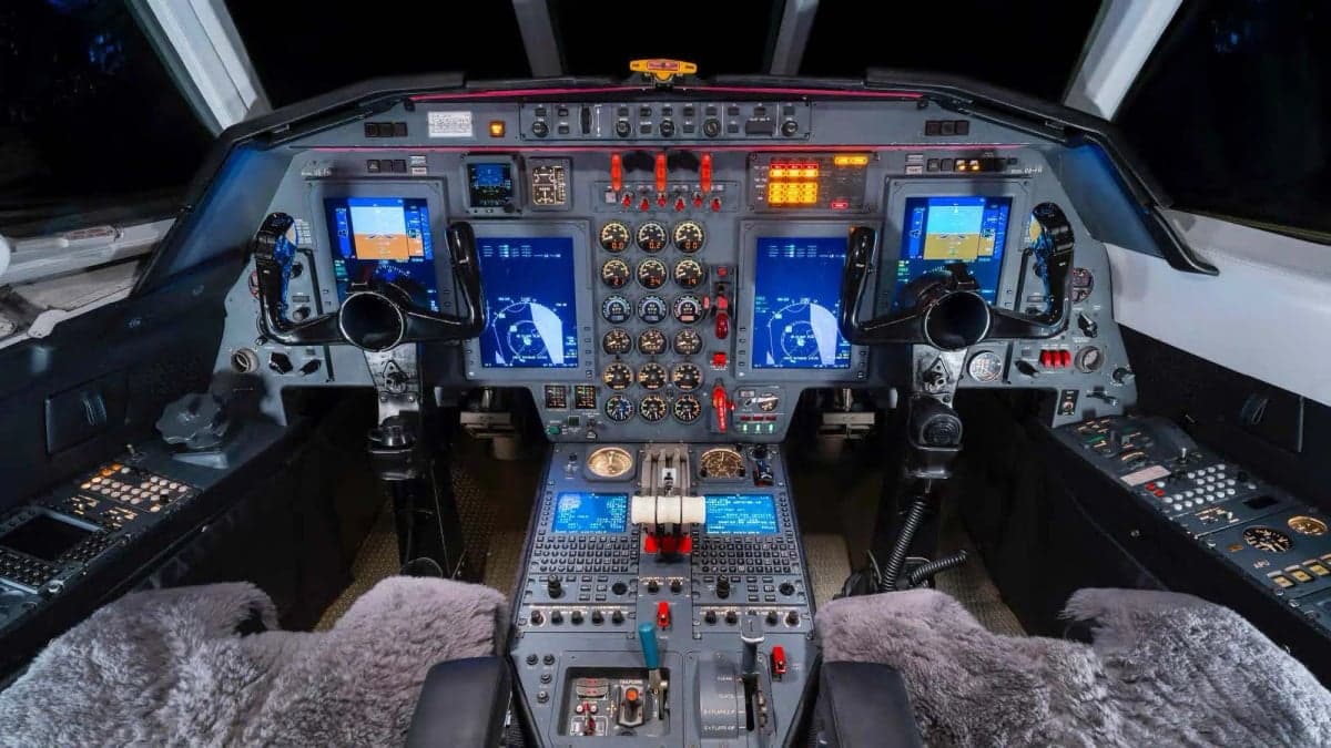 The cockpit of a Falcon jet with many instruments and screens.
