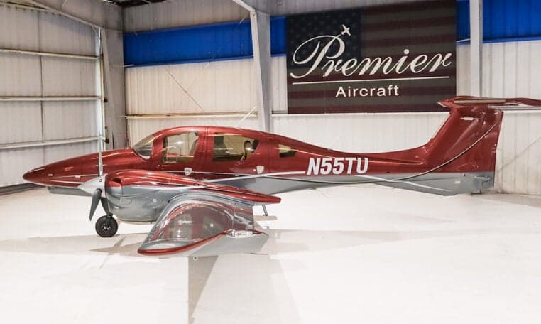 Side view of a Diamond DA62 aircraft with registration N55TU inside a hangar.