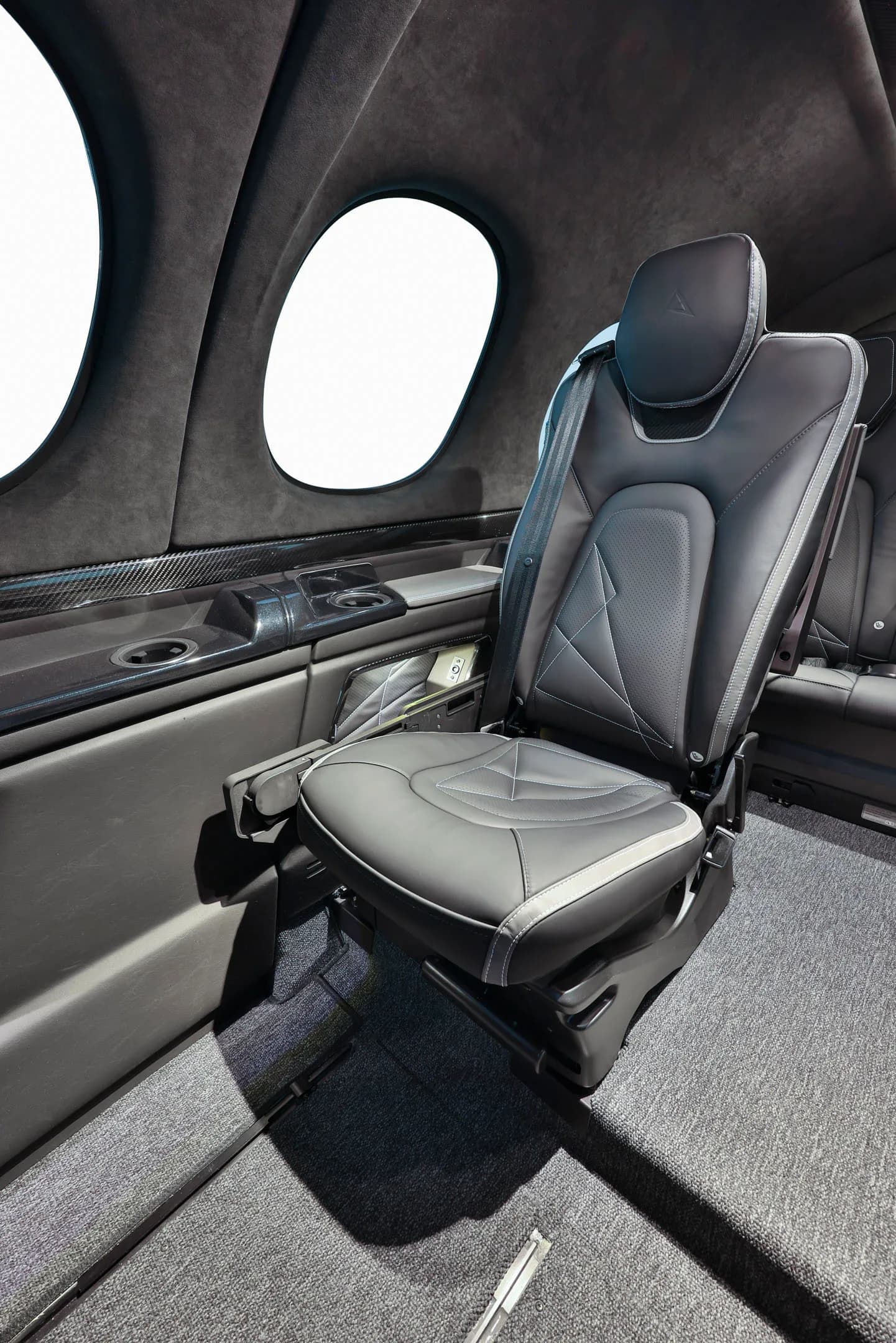 A single dark grey leather passenger seat with white stitching is visible in the Cirrus Vision Jet cabin.