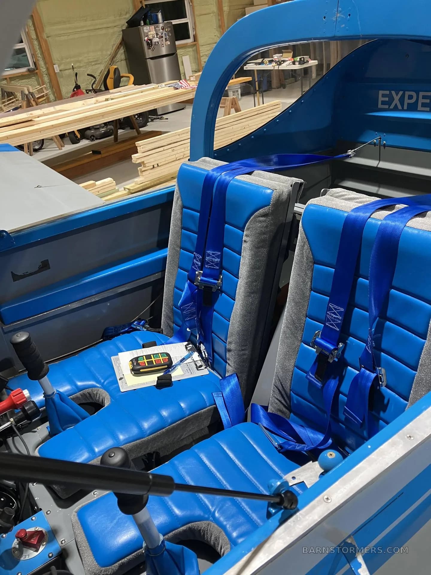 The interior cabin of the experimental aircraft, featuring two blue and gray seats with blue harnesses.