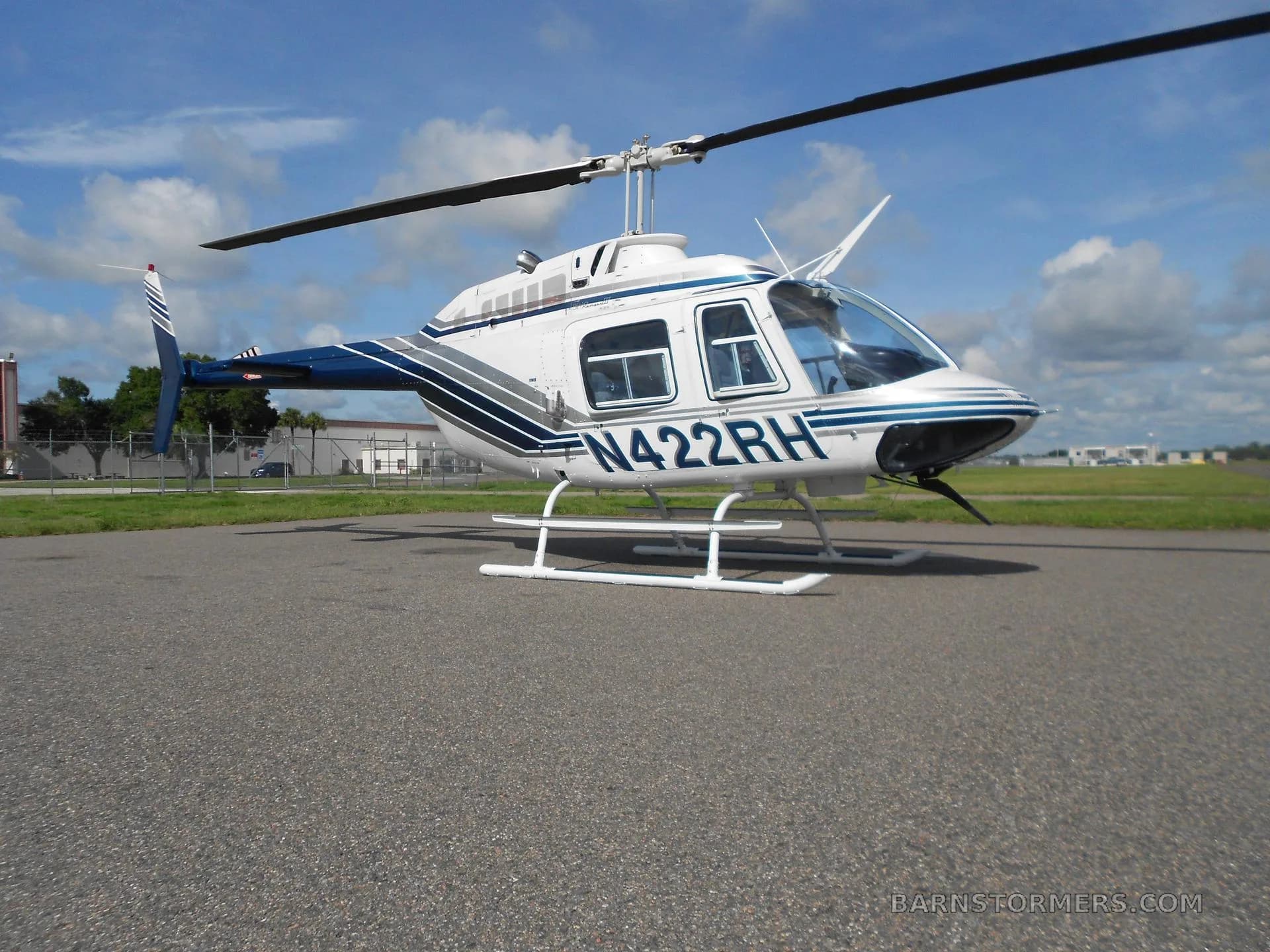 A white and blue Bell 206 helicopter (N422RH) parked on an asphalt apron, viewed from a slightly different angle.