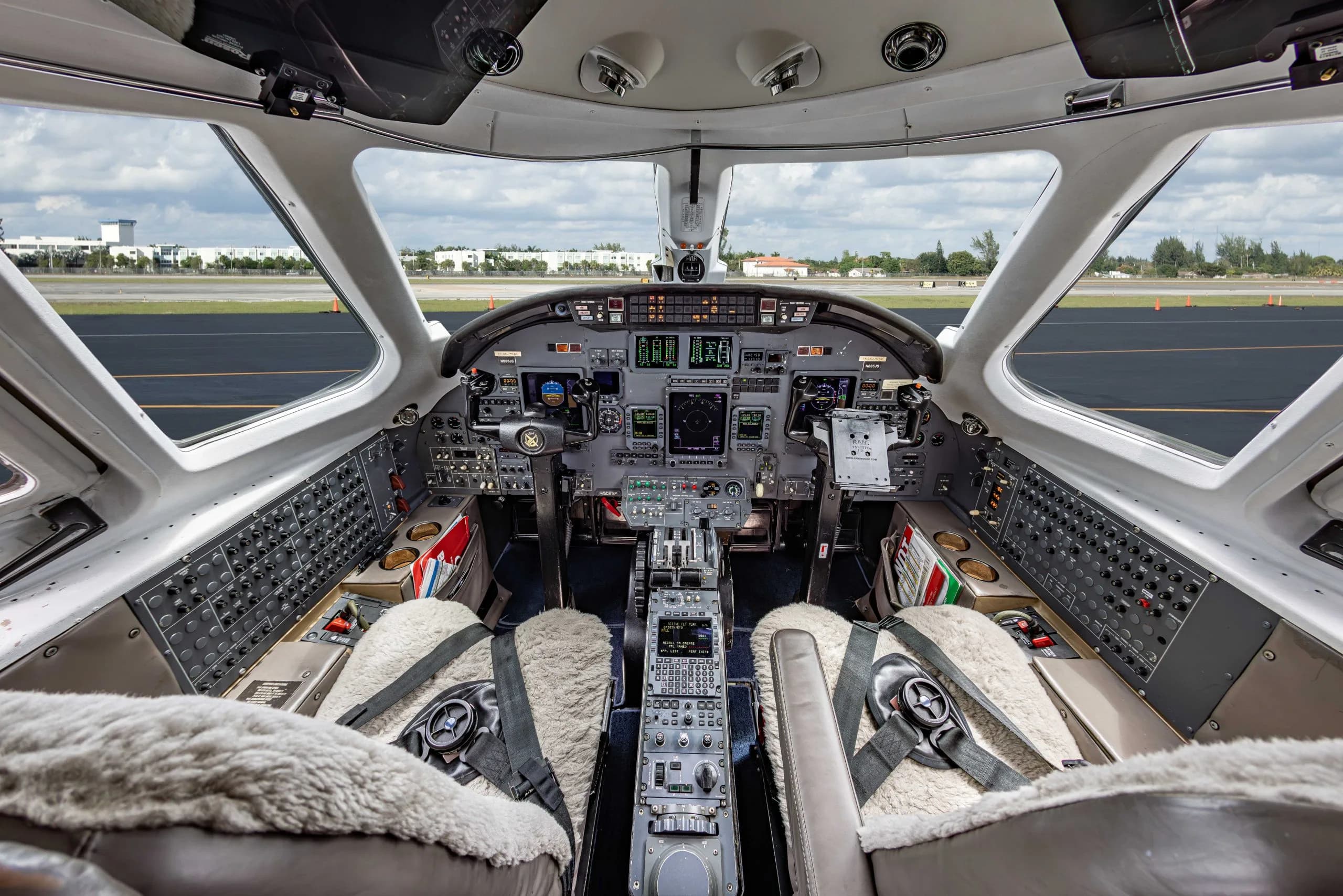 View of the aircraft's cockpit with instrument panel and sheepskin seat covers.