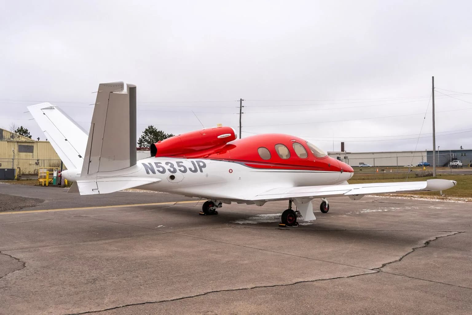 Right side view of a red and white Cirrus Vision Jet (N535JP) on the tarmac.