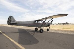 Side view of a gray and red Cubcrafters XCub on the tarmac.