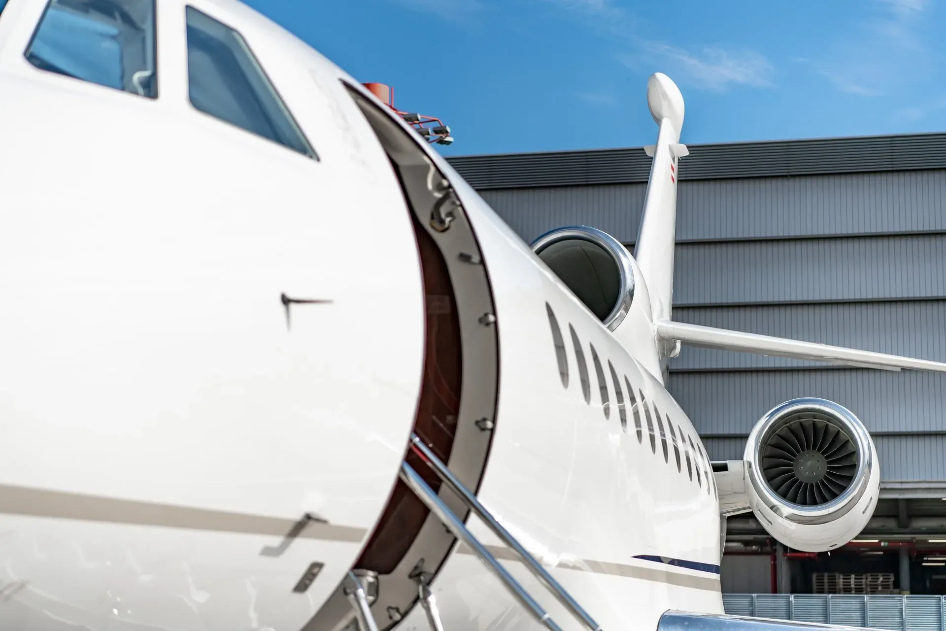 A close-up view of the open main door, front fuselage, and engine of a white business jet.