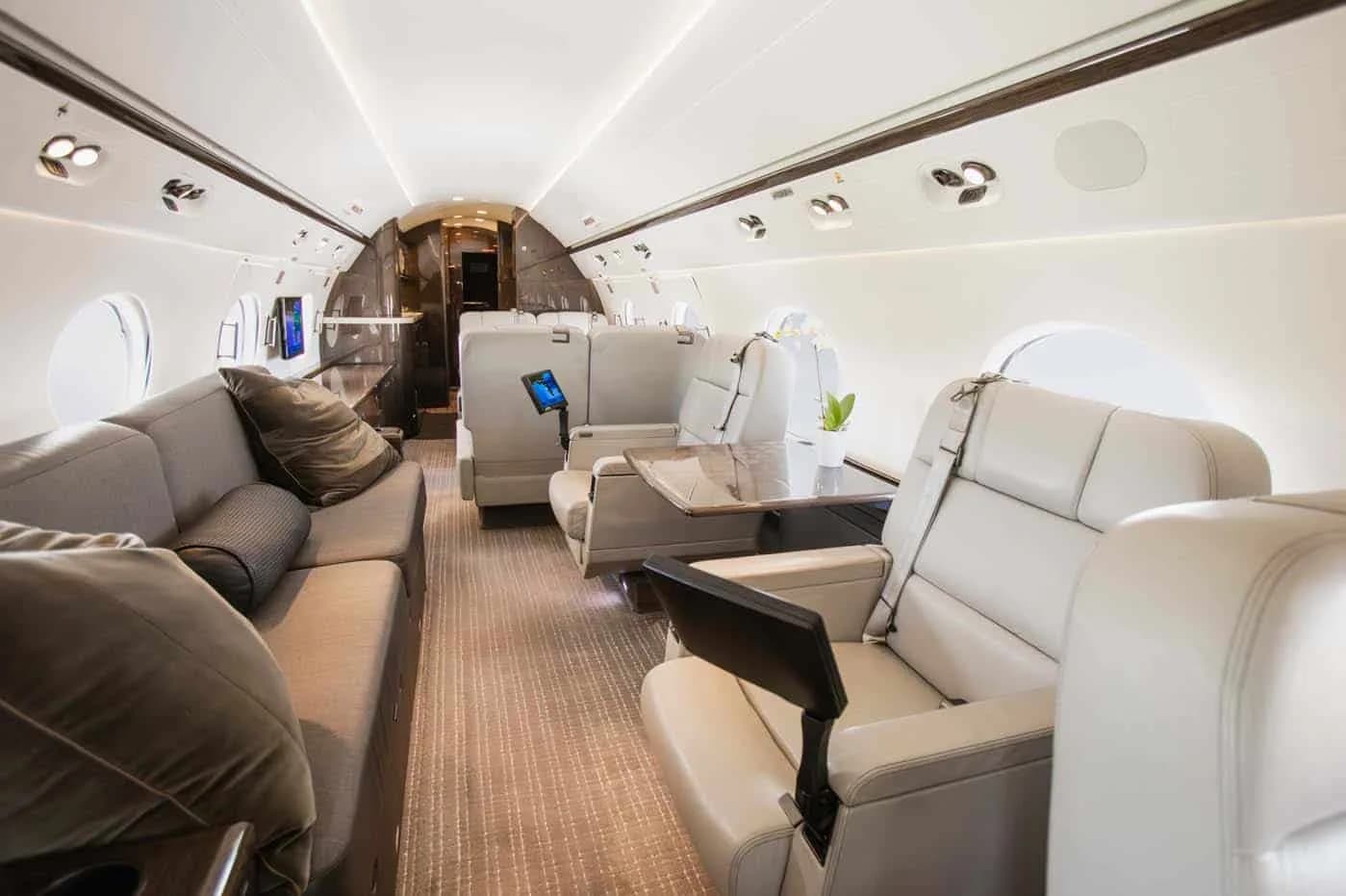 A comfortable aircraft cabin with a sofa lounge area and individual light-colored seats.