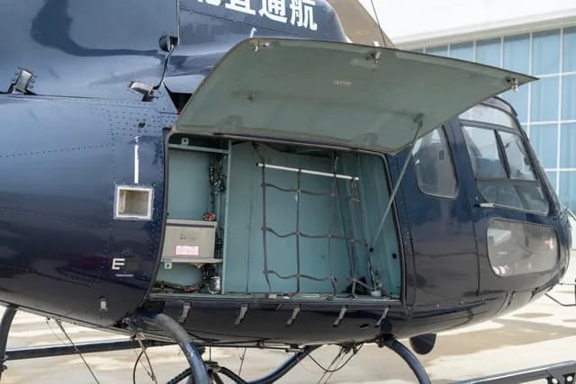 A close-up view of the open cargo compartment on the side of a dark blue helicopter.